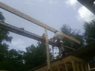Carpenter setting a ridge beam over a new addition frame — Ice Dam Removal by Roofing Brothers in East Freedom