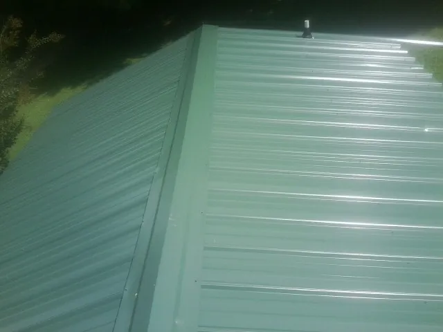 New green metal panels meeting at the ridge of a roof — Flat Roof Repair work by our crew in East Freedom