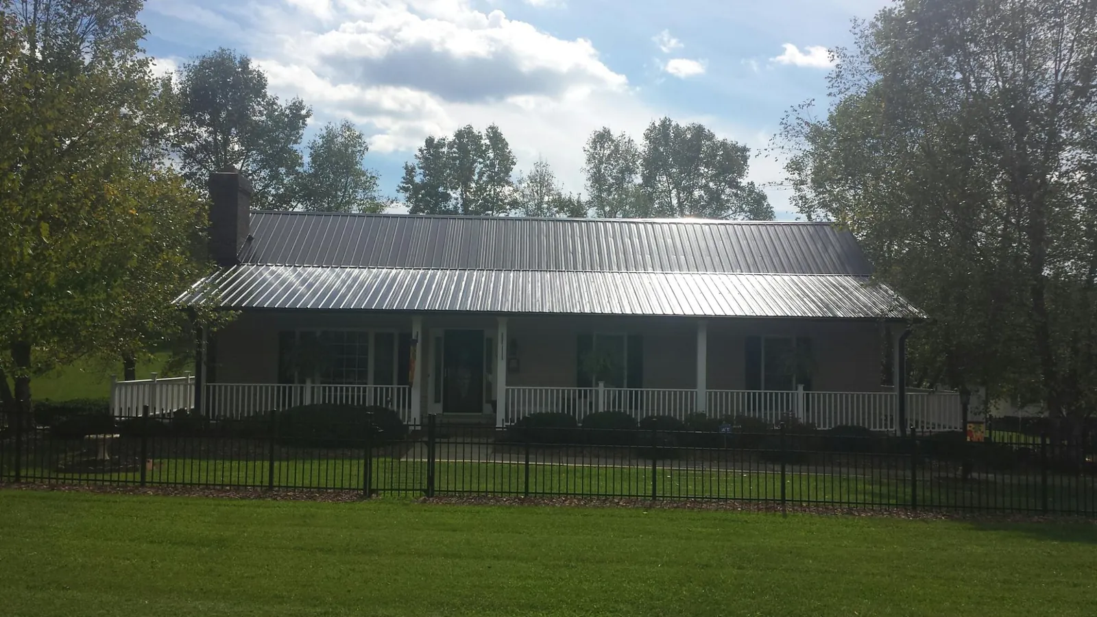 Gray metal roof on a brick ranch with a full width front porch — Gutter Guard Installation work by our crew in East Freedom