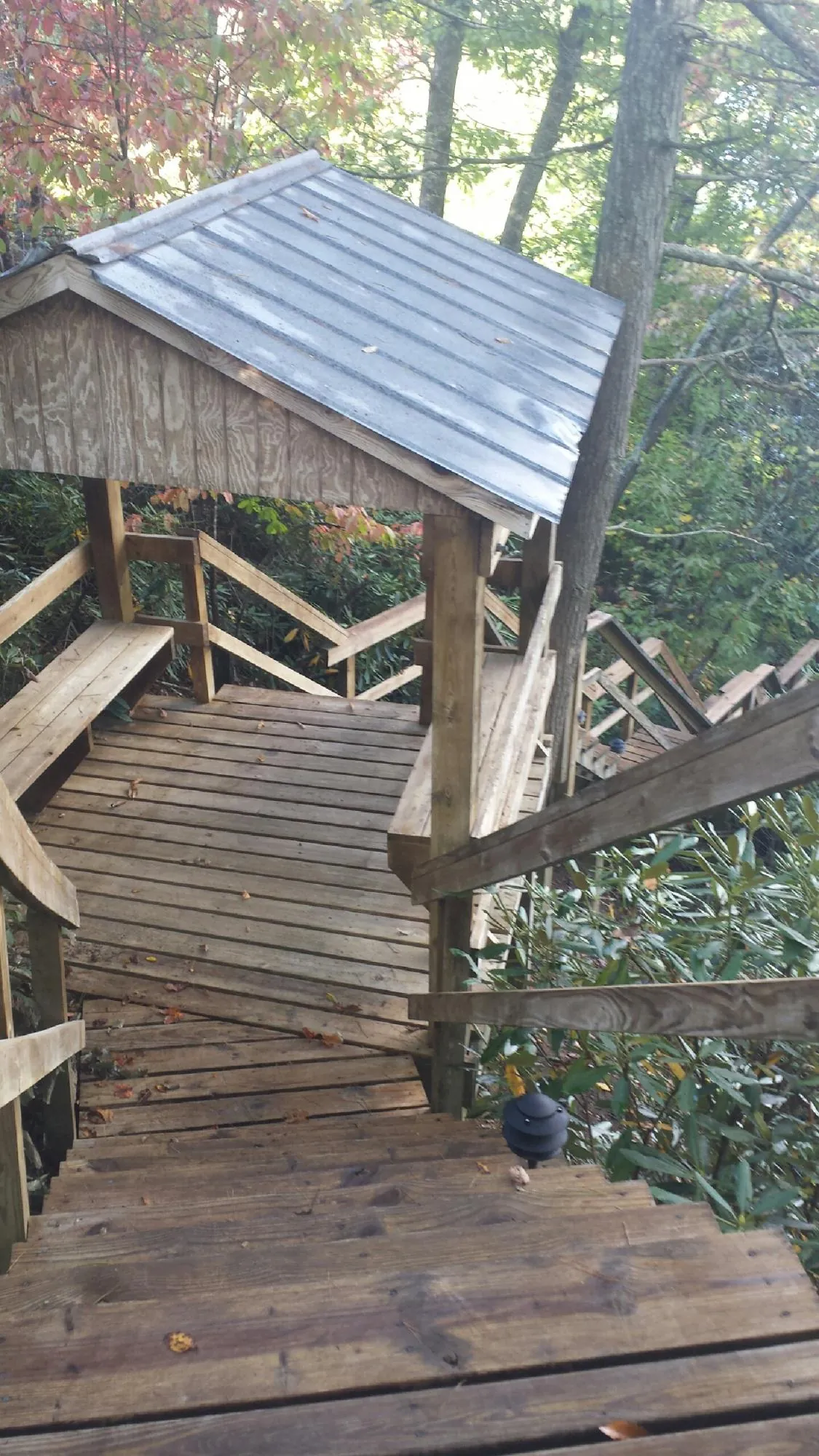 Metal roofed shelter over wooden steps on a wooded walkway — Skylight Repair & Installation work by our crew in East Freedom