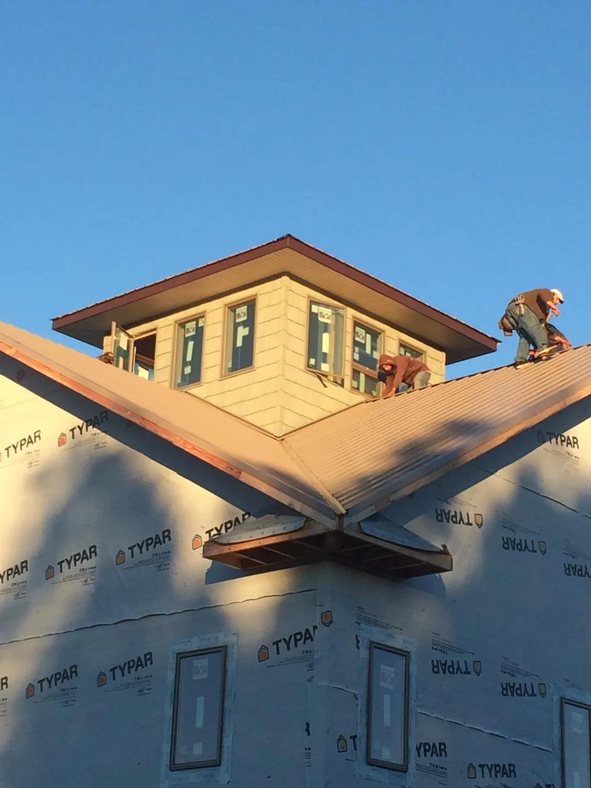 Roofers working around a rooftop cupola on a new metal roof at sunset — Roof Waterproofing in East Freedom by Roofing Brothers